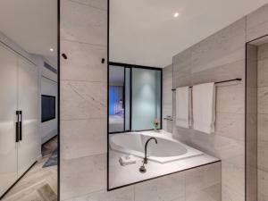悉尼The Star Grand Hotel and Residences Sydney的带浴缸和玻璃墙的浴室
