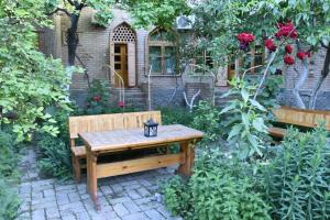 撒马尔罕ANTICA Family Guest House的坐在花园中间的木凳