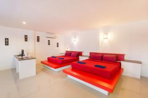 通萨拉大神田海滩别墅度假村的白色客房的两张床,配有红色枕头