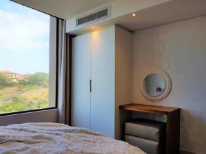 巴利托Zimbali Suites 507的一间卧室配有一张床、镜子和窗户
