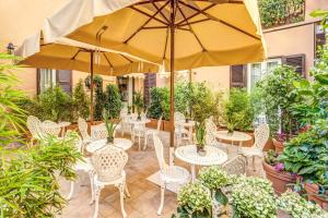 罗马Charme Spagna Boutique Hotel的一个带桌椅和遮阳伞的庭院