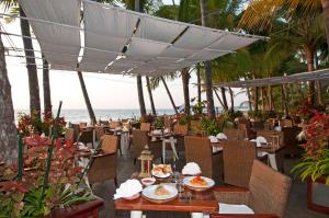 额布里桑德威度假酒店的餐厅配有桌椅,位于海滩的背景