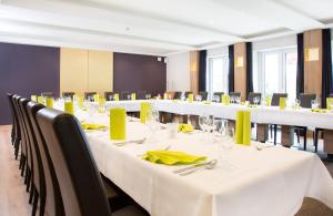 利普施塔特Parkhotel Lippstadt的一间会议室,配有白色的桌子和椅子,并配以黄色的餐巾