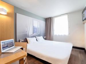 沙特尔B&B HOTEL CHARTRES Oceane的酒店客房配有一张床铺和一张书桌上的笔记本电脑