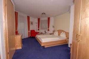 玛丽亚阿尔姆伯格乌尔斯劳霍夫温泉酒店的一间卧室配有一张床和一张红色椅子