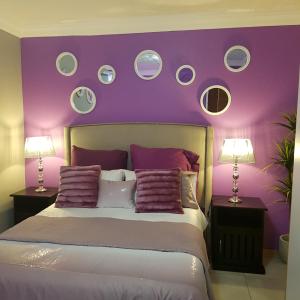 贝拉贝拉Dinaledi House的一间卧室设有紫色的墙壁和一张带枕头的床
