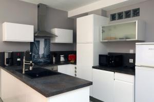 鲁西隆地区卡内Superbe Appartement Vue mer的厨房配有白色橱柜和黑色台面