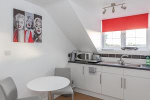 史云顿Park View Studio - Lydiard Millicent Swindon Wiltshire的小厨房配有白色橱柜和白色桌子