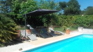 朗通Chambres d'Hotes des Ecureuils的一组椅子和一把遮阳伞,位于游泳池旁
