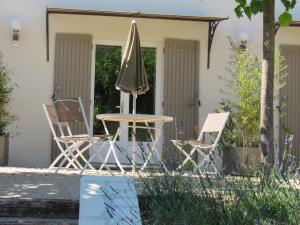 克里隆勒布拉沃Résidence de gîtes La Sidoine du Mont-Ventoux的桌子、椅子和遮阳伞位于房子前