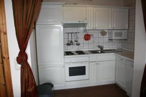 博尔滕哈根Zur alten Schmiede I (Mitte)的厨房配有白色橱柜和炉灶烤箱。