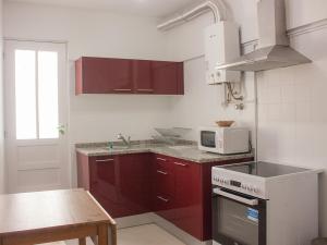波瓦-迪瓦尔津Varzim Guesthouse的厨房配有红色橱柜和白色微波炉