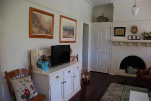 贝里马Hillside Cottage Berrima的一间带电视和壁炉的客厅