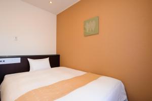 宇都宫宇都宫市岐山酒店 的一间卧室配有一张白色的床和橙色的墙壁
