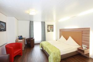 Ennigerloh胡博图斯酒店的酒店客房,配有一张床和一张红色椅子