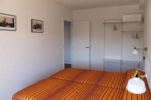 隆达布埃纳维斯塔公寓的一间卧室配有一张带橙色条纹床罩的床