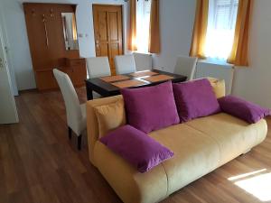 莫雄马扎尔古堡Apartman Kaszás Central的客厅配有沙发和带紫色枕头的桌子