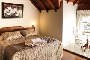 格拉玛多Hotel Aconchego da Serra的卧室配有1张床、1张桌子和1把椅子