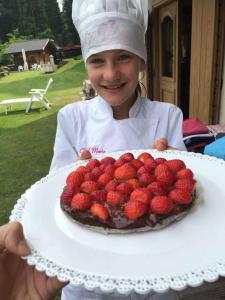 费拉迪普利米罗B&B Maso al Cervo的一只小女孩拿着一个草莓蛋糕