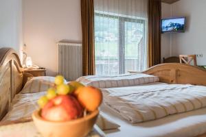 海利根布卢特鲍尔勒旅馆的一间卧室设有两张床,桌子上放着一碗水果