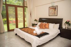 浦那Hermitage Suites Koregaon Park Garden & Terrace Room的一间卧室配有一张带枕头的大床