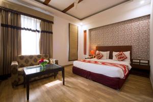 新德里Hotel Krishna - By RCG Hotels的酒店客房配有床、沙发和桌子。