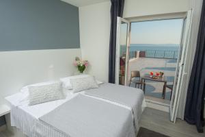珀德垂那Seaside Luxury Suites的一间白色卧室,配有床和阳台