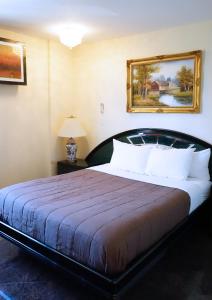 皇后区Paris Suites Hotel的卧室配有一张大床,墙上挂有绘画作品