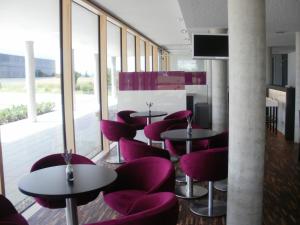 乌尔姆乌尔姆iQ酒店的餐厅设有紫色椅子、桌子和窗户