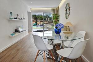 阿尔布费拉3 Villas - Praia da Falesia的一间设有玻璃桌和白色椅子的用餐室