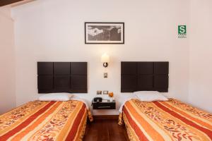 库斯科Hostal & Apartments El Triunfo的两张位于酒店客房的床,配有两张sidx sidx单人床