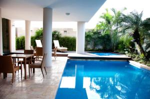 瓜亚基尔马尔奇丽斯酒店的房屋旁的游泳池配有桌椅