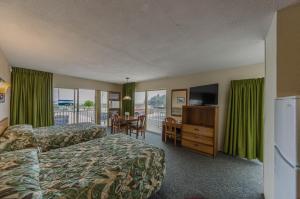 威尔伍德克拉斯特Attache Motel的酒店客房设有两张床、一张桌子和一台电视。