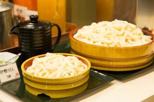 伊势市Sanco Inn Iseshi-Ekimae Shikinoyu的两堆黄碗面在柜台上
