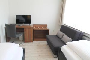鲁尔河畔米尔海姆翰斯卡斯坦尼恩霍夫酒店的客厅配有沙发和书桌及电视