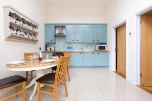 Aldringham萨福克诺迪什尔度假屋的厨房配有蓝色橱柜和桌椅
