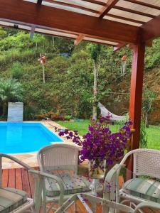 彼得罗波利斯Loft Aconchego da Serra的一个带桌椅的庭院和一个游泳池