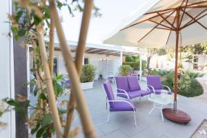 拉古萨码头Marina Loft Sicily的一个带紫色椅子和遮阳伞的庭院