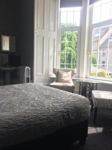 阿伯丁Lochnagar Guest House的一间卧室配有一张床、一把椅子和窗户。