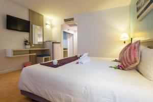 卡伦海滩ON Hotel Phuket - SHA的一间卧室配有一张白色大床,床上有鲜花