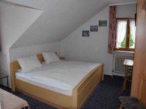 辛斯海姆Hotel Gästehaus Sonne的一间卧室配有一张带白色床单的床和一扇窗户。
