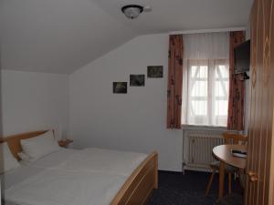 辛斯海姆Hotel Gästehaus Sonne的一间卧室配有一张床、一张桌子和一个窗户。