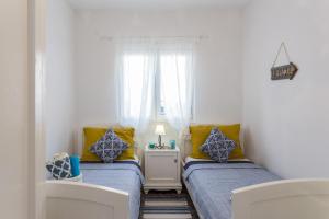 ProžuraNono Frano的小客房内的两张床,配有黄色和蓝色枕头