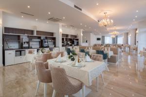 罗戈兹尼察Hotel Perla的一间带白色桌椅的餐厅和一间厨房
