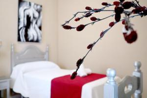 拉卡尔洛塔Hostal Victoria的一间卧室配有床,另一间设有浆果树枝