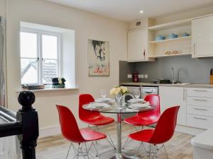 科尔福德Pomegranate的厨房配有桌子和红色椅子
