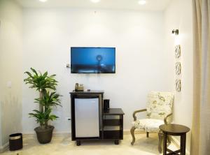 拉斯塔布拉斯Hotel Presidente Las Tablas的客厅配有椅子和墙上的电视