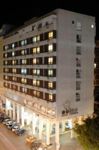 巴热奥比诺巴吉酒店的一座白色的大建筑,前面有汽车停放