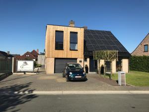 HerzeleQ Studio的一辆停在房子前面的汽车,房子拥有太阳能屋顶