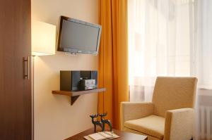 波恩梅塞德斯城市酒店的一间房间,墙上有椅子和电视